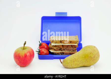 Blue breadbox filled with sandwiches and tomatoes, fruit in foreground Stock Photo