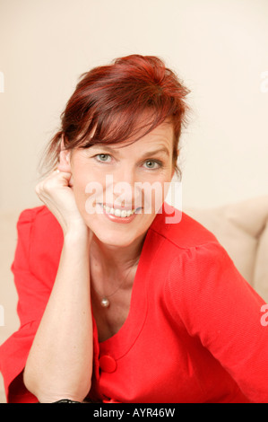 Middle-aged woman wearing red dress, smiling Stock Photo