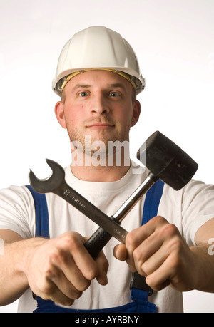 Construction worker holding tools, open-end wrench and hammer Stock Photo