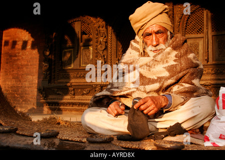 Old man sitting cross-legged in front of Dattatreya Temple in Bhaktapur, Nepal, Asia Stock Photo