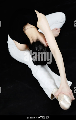 Stretch it out - Ballet. Young ballerina doing warm-up exercises while