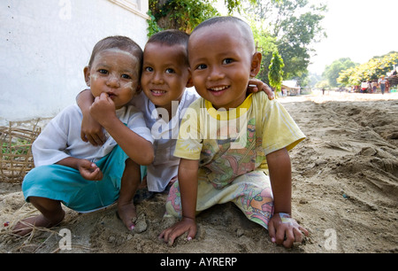 Three young boys squatting on a dusty road in Mingun, Mandalay, Myanmar (Burma), Southeast Asia Stock Photo