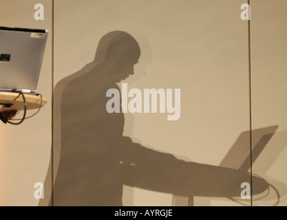 shadow of a man working laptop on the wall Stock Photo