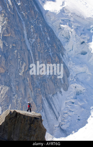 Mountain climber standing on a rock platform in front of the edge of a glacier on Mont Blanc, Chamonix, France Stock Photo