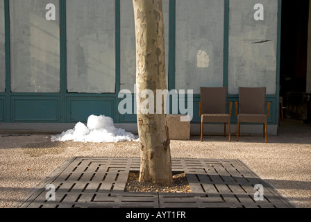 a pile of disregarded ice cubes and a pair of empty chairs sit outside a closed cafe in france Stock Photo