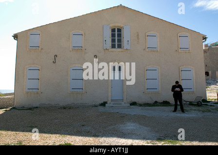 a lone standing man in dark suit reads a book in front of old building on the Ile d'IF Stock Photo