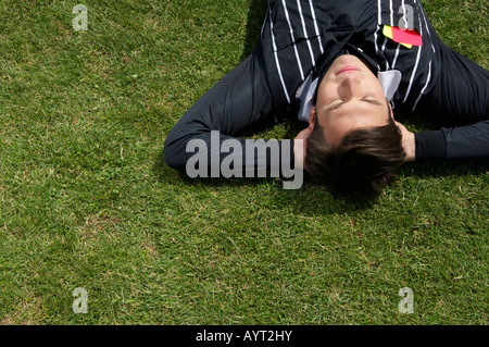 Relaxed referee lying on soccer field Stock Photo