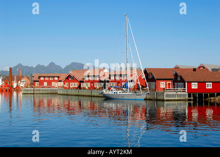 Red Rorbuer houses, fishing village reflected on the smooth surface Kabelvag Harbour, Lofoten, Norway Stock Photo