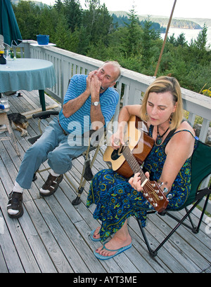Happy friends with musical instruments relaxing near the river outdoors ...