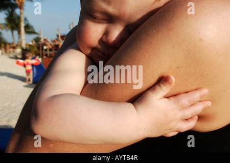 Netherlands Antilles Curacao a baby boy sleeping in the arms of his mother Stock Photo