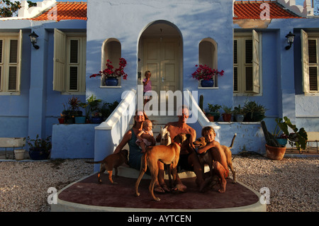 Netherlands Antilles Curacao expat family posing on the steps of their historical colonial Dutch cottage Stock Photo