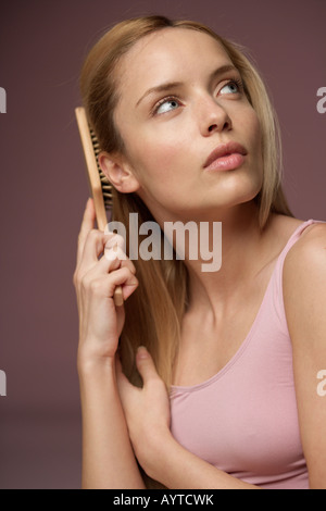 Young blonde woman brushing her hair, close-up Stock Photo