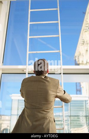 Businessman standing on a ladder Stock Photo