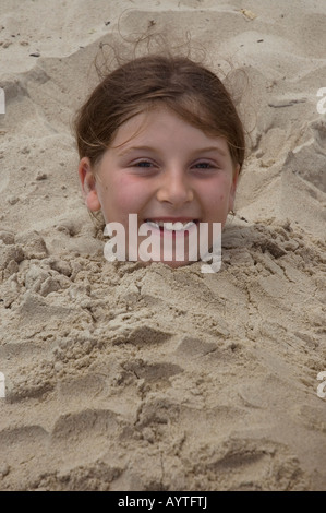 Young girl buried in sand Stock Photo