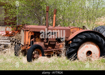 An old Case tractor sits derelict in a grass-choked area next to a highway near Watonga, Oklahoma, USA. Stock Photo