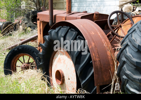 A rusting, old Case tractor sits derelict in a grass-choked area next to a highway near Watonga, Oklahoma, USA. Stock Photo