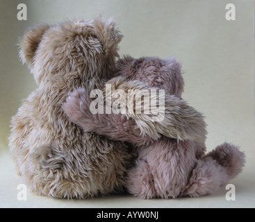 two old teddy bears, each with an arm around the other Stock Photo