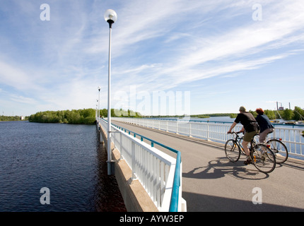 Bikers on a bridge crossing River Oulujoki from Hietasaari islet to Korkiasaari islet Oulu , Finland Stock Photo