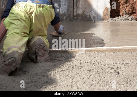 workman in hivis trousers laying concrete base and using float to smooth surface Stock Photo
