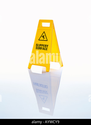 A bright yellow warning floor sign saying 'Slippery surface' on a wet / icy background Stock Photo