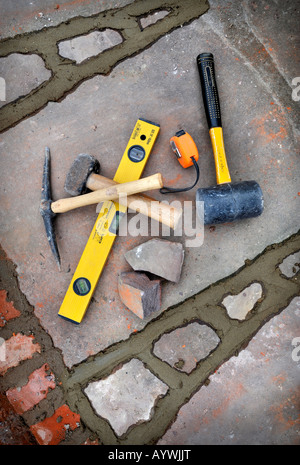 BUILDERS TOOLS AMONGST RECENTLY POINTED JOINTS AWAITING BRUSHING OUT ON A PATIO LAID WITH NATURAL STONE SLABS UK Stock Photo