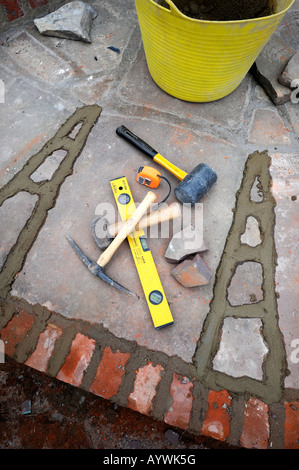 BUILDERS TOOLS AMONGST RECENTLY POINTED JOINTS AWAITING BRUSHING OUT ON A PATIO LAID WITH NATURAL STONE SLABS UK Stock Photo