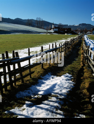 Winterlandschaft, Zaun, eingezaeunter Weg, Viehgatter, Restschnee, Dorfkirche von Weitnau-Kleinweiler-Hofen, Allgaeu, Schwaben, Bayern Stock Photo