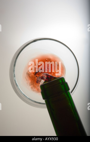 Top down view of red wine being poured into glass from green wine bottle neck Stock Photo