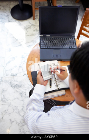 a man using PDA in front of laptop computer Stock Photo