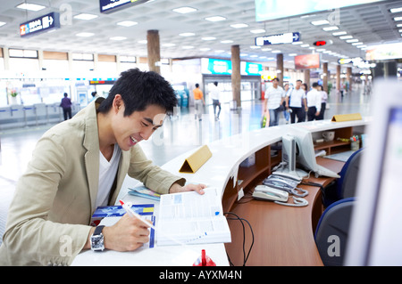 a man drawing up a document with looking a book in the reception of airport Stock Photo