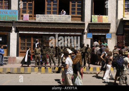 Police and army personnel stand outside the State Bank Of India as tourists walk by in Leh ladakh India. Stock Photo