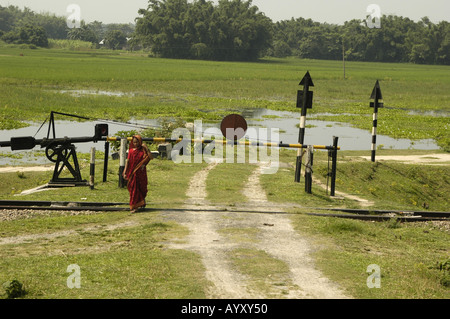 A traffic barrier with woman in sari as seen from Indian Railway train Stock Photo