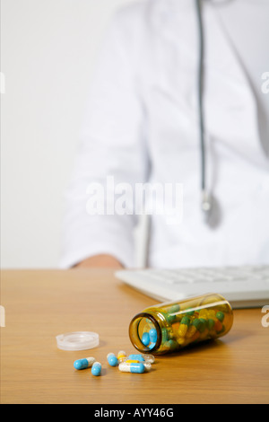 Open flask with capsules, doctor  in background Stock Photo