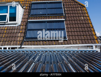 Solar thermal evacuated collecting tubes on a flat roof and a pitched roof used to heat hot water in a Weymouth guest house Stock Photo