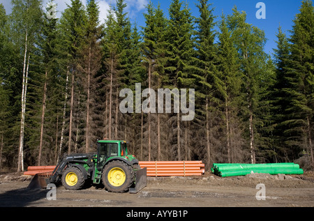 Tractor and drainage pipes at road building site , Finland