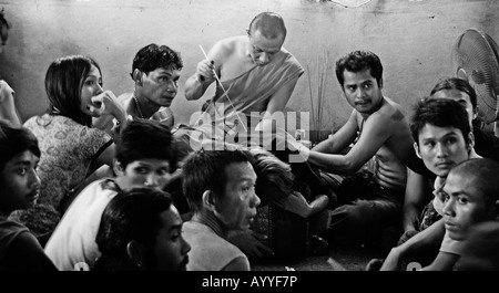 Man being tattooed by a budhist monk during the Wat bang Phra tattoo festival in Thailand Stock Photo