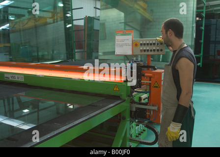 lFactory worker operating laminated glass cutting machine in glass factory Stock Photo