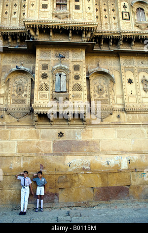 India, Rajasthan, Jaisalmer. On the outside walls of the city's largest haveli, street life goes on as normal. Stock Photo