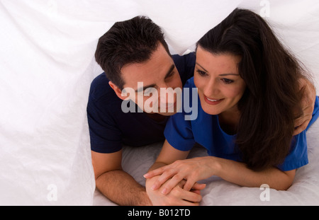 Dating couple happy together under covers in bed Stock Photo