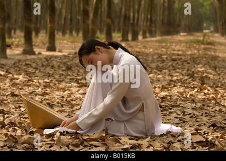 Vietnamese schoolgirl in a rubber tree plantation during breaktime Stock Photo