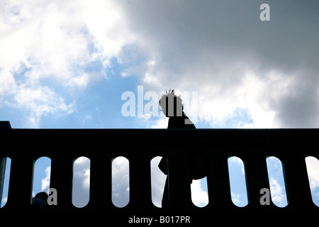 Silhouette of a person walking across bridge before storm hits Stock Photo