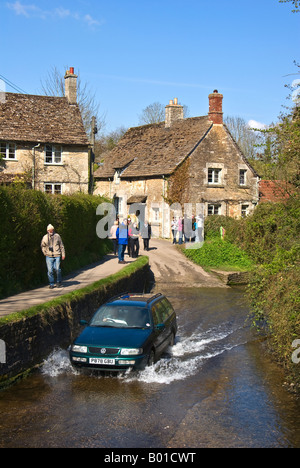 An estate car splashes through the ford over a brook through Lacock village Stock Photo