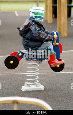 Childrens Playground with Soft Play Safety Surface Boy on Spring Rocker Equipment Stock Photo