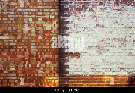 Detail of once stylish brick wall painted white with rounded black edge bricks next to crudely bricked in doorway Stock Photo