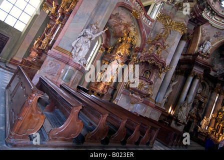 Horizontal wide angle perspective of the old wooden pews inside St.Nicholas Church 'Chram sv Mikulase' in Mala Strana. Stock Photo