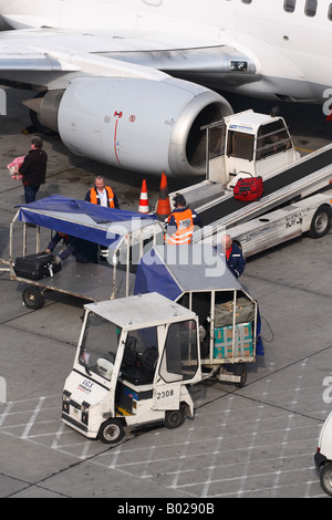 Airport baggage luggage suitcase trolley vehicle loading bags onto a jet airliner Stock Photo