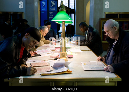 People fill in tax forms in the lobby of the Farley Post Office in New York 15 April 2008 Stock Photo