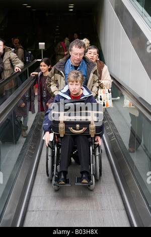 Wheelchair passenger arriving Eurostar train platform via moving walkway. Kings Cross/Saint Pancras International station London Stock Photo