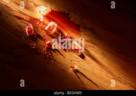 BROKEN WINE GLASS LYING SMASHED ON WOODEN FLOOR WITH SPILLED WINE Stock Photo