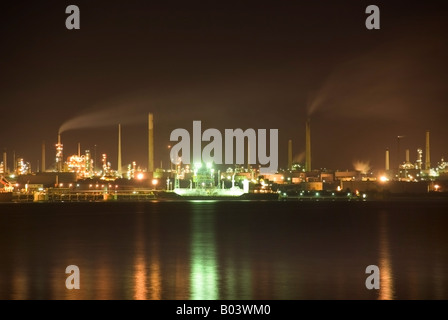 Refinery smoke, lights and water  Night view across the Solent to Fawley oil refinery and chemical works near Southampton Stock Photo